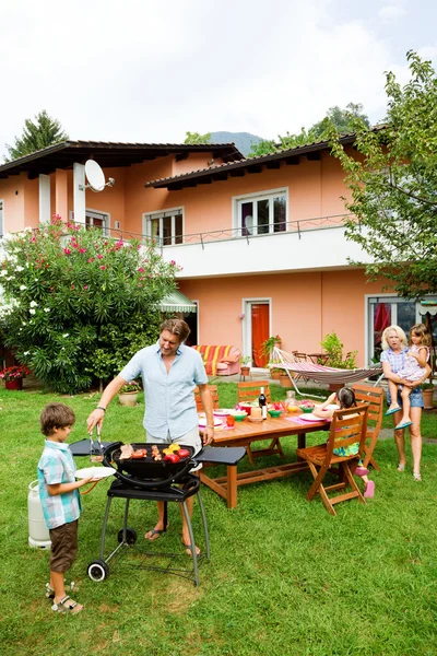 Famiglia che fa un barbecue in giardino, mangia — Foto Stock