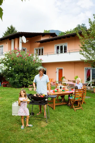 Familia haciendo una barbacoa en el jardín, comiendo — Foto de Stock