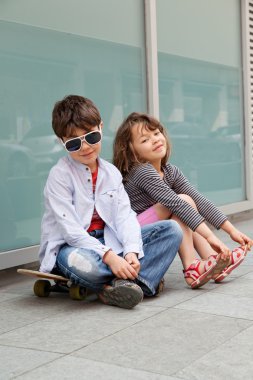 Kardeşim bir duvarın önünde oturan kız kardeşi