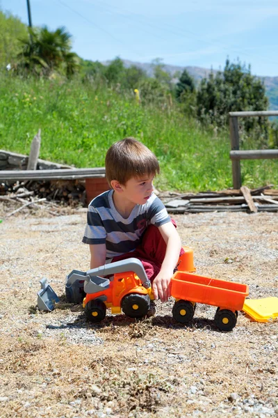 Ragazzino che gioca con auto giocattolo di plastica — Foto Stock