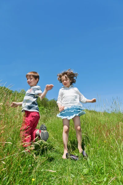 Two children jumping in a meadow — Stock Photo, Image