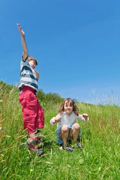 Two children jumping in a meadow — Stock Photo, Image