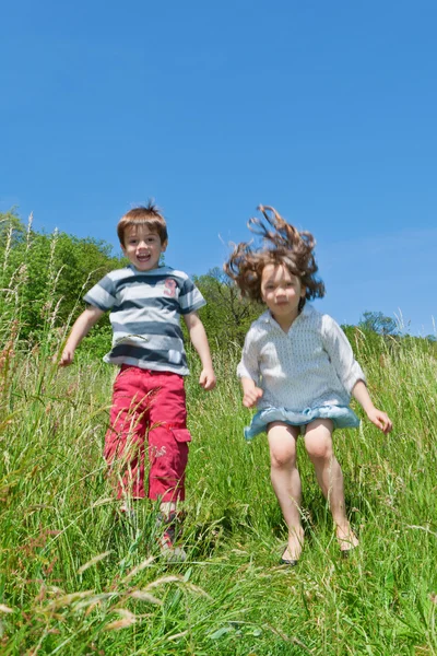 Dos niños saltando en un prado — Foto de Stock