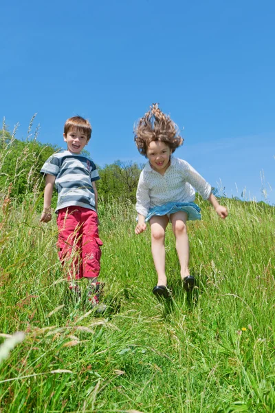 Dos niños saltando en un prado — Foto de Stock