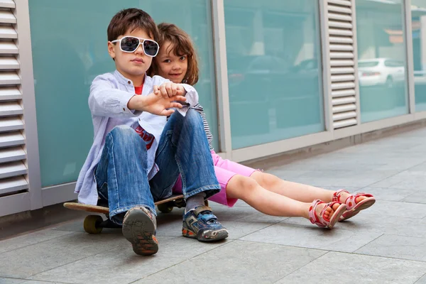 Hermano una hermana sentada frente a la pared — Foto de Stock