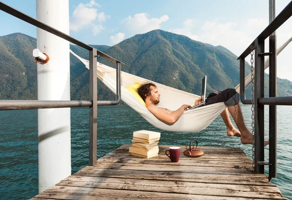 Young man with laptop at lake — Stock Photo, Image