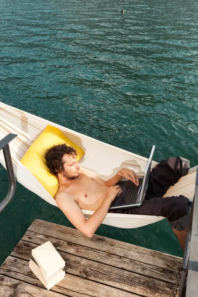 Joven con portátil en el lago — Foto de Stock