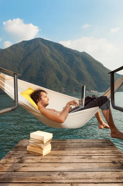 Young man with laptop at lake — Stock Photo, Image