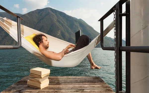 Young man with laptop at lake — Stock Photo, Image