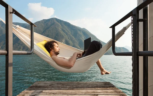 Young man with laptop at lake — Stock Photo, Image