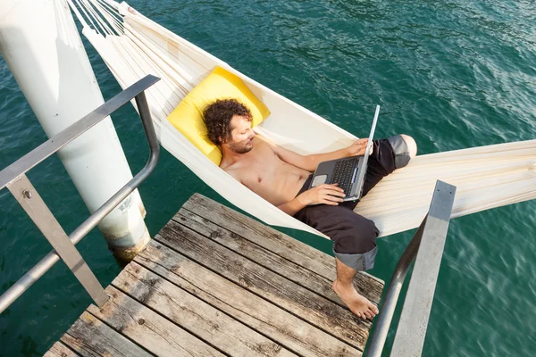 Young man with laptop at lake — Stock Photo, Image