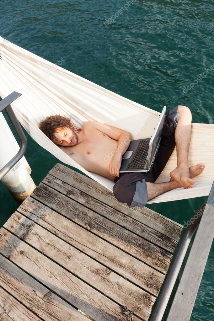 young man with laptop at lake