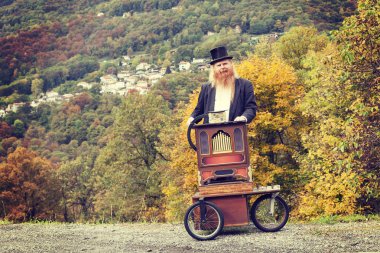 red hair and beard elegant man playing his cart organ around clipart