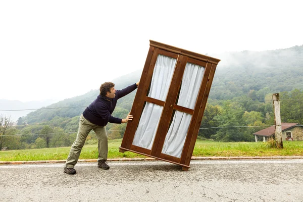 Homem move guarda-roupa, está fazendo um movimento — Fotografia de Stock