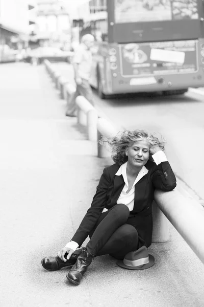 Frau sitzt am Straßenrand — Stockfoto