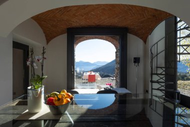 Camdan bir masası ve penceresinden dağların güzel manzarası olan küçük bir odada. Güneşli bir gün.