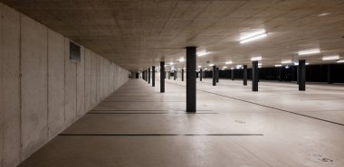 Açık renkli, siyah çizgili ve sütunlu yeni bir otoparkın ön görüntüsü. İçeride kimse yok, gece sahnesi..