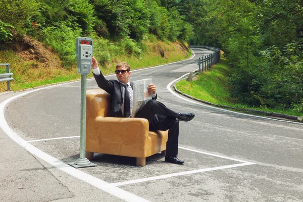 Businessman sitting on armchair in the middle of the road — Stock Photo, Image