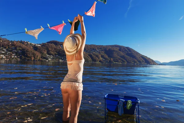 Waman, hanging clothes by the lake — Stock Photo, Image