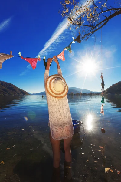 Waman, hanging clothes by the lake — Stock Photo, Image