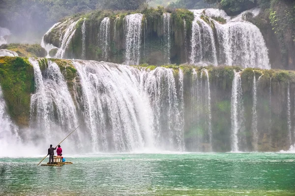 Tourists on a bamboo raft near a waterfall — Stock Photo, Image