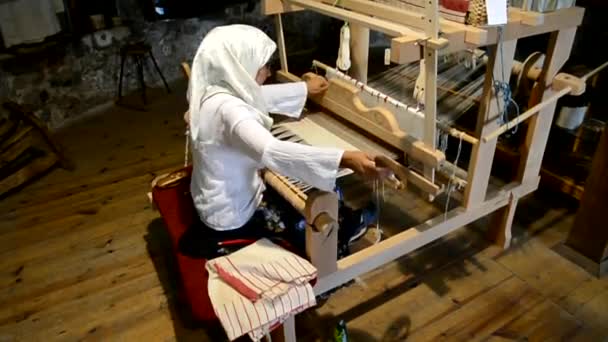 Пожилая женщина производит ткань на ткацких станках — стоковое видео