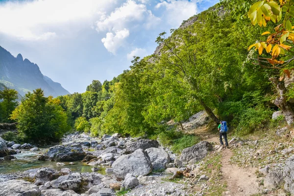 Tourist walking on the footpath along the river in the mountains — Stock Photo, Image