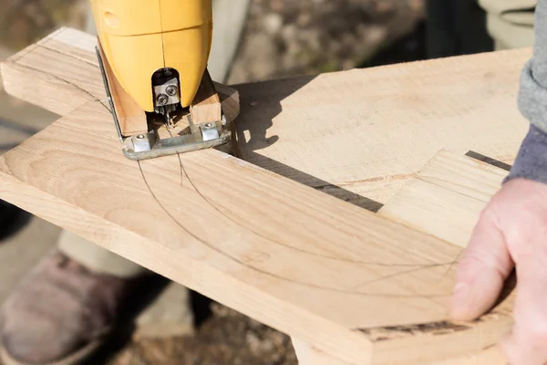 Carpinteiro está cortando uma placa com fretsaw — Fotografia de Stock