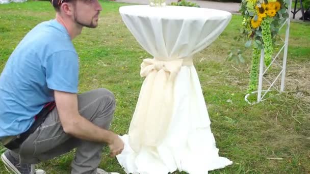 Kwiaciarnia człowieka w pracy zawiązać supeł na biały stół. — Wideo stockowe