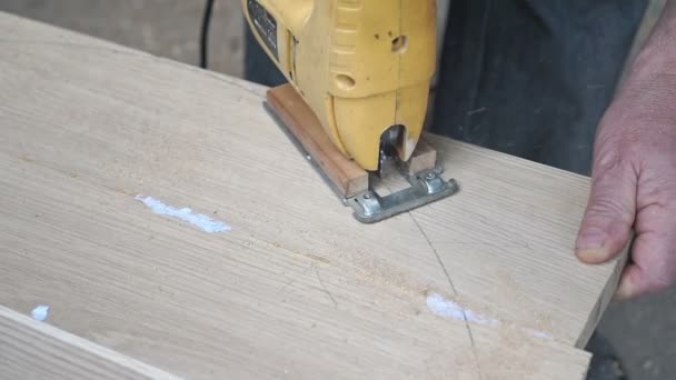 Carpenter is cutting a board with fretsaw — Stock Video