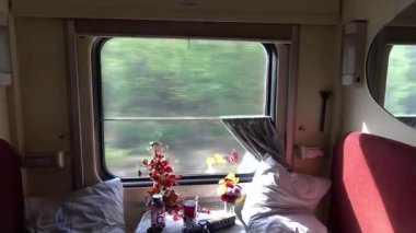 Trenin camından geçen yeşil ağaçlar, sokaktaki trafik gibi. Demiryolu boyunca ilerleyen modern ve rahat bir aracın görüntüsü..