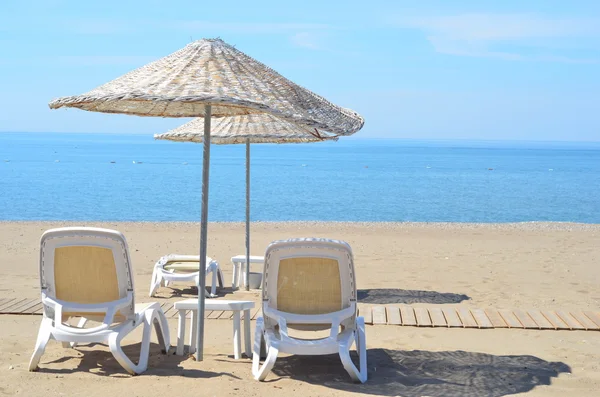 Cadeiras de praia e guarda-chuva em uma praia — Fotografia de Stock