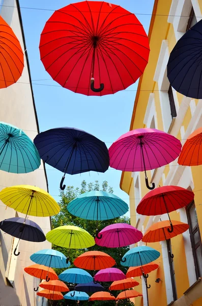 Paraguas coloridos instalados en la calle de la ciudad sobre fondo azul cielo —  Fotos de Stock