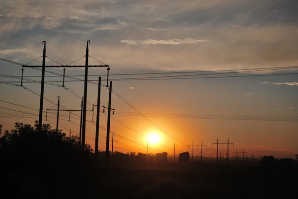 Pylons da eletricidade, linhas de poder de encontro ao por do sol — Fotografia de Stock