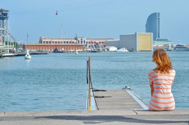 Barcelona'da pier üzerine oturan genç bir kadın arkası