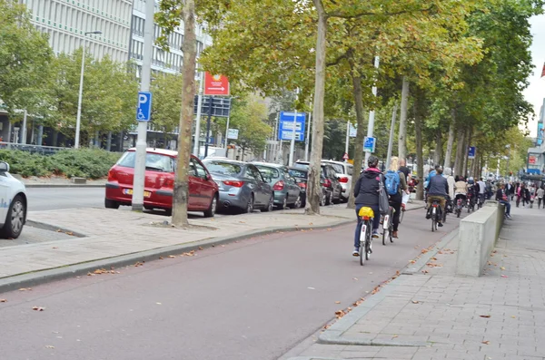 Pessoas não identificadas atravessando a rua de bicicleta . — Fotografia de Stock