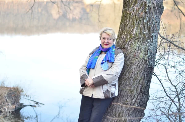 Portret kobiety starsze, opierając się na drzewo — Zdjęcie stockowe