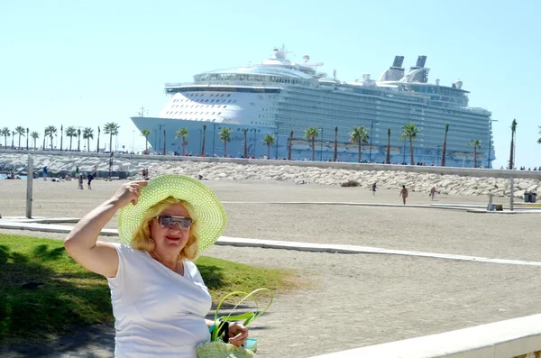 Vrouw in zomer hoed in een dok, grote cruise schip op achtergrond — Stockfoto