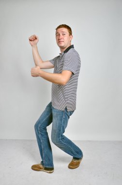 Handsome young man dancing, full length portrait, grey background