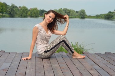 Göl kenarında oturan güzel genç kadın