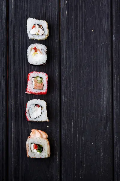 Rollos Sushi Japoneses Tumbados Una Tabla Madera Negra Vista Desde —  Fotos de Stock