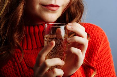 Partide ellerin kokteyl tutmasını yakından izleyin. Kırmızı kazaklı kadın elinde şampanya bardağıyla