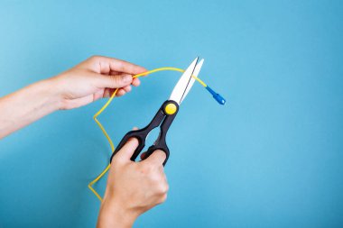 Optik fiberi makasla yok et. Mavi üzerine izole edilmiş.
