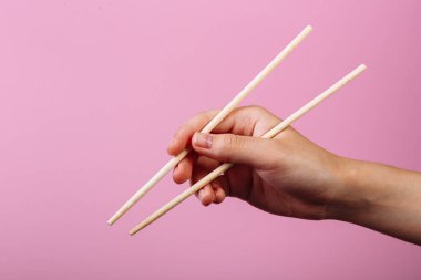 Öğretim: yemek çubuklarını yemek çubuklarıyla nasıl tutulacağını. Pembe arka planda izole edilmiş. Adım 4