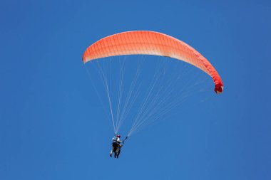 Mavi Paraglider, güneşli bir günde bulutlarla gökyüzüne uçan bir turist ile ikili eğitmen.