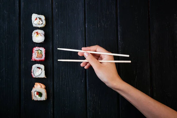 Mão Feminina Leva Pauzinhos Rolos Sushi Com Pauzinhos Chineses Deitado — Fotografia de Stock