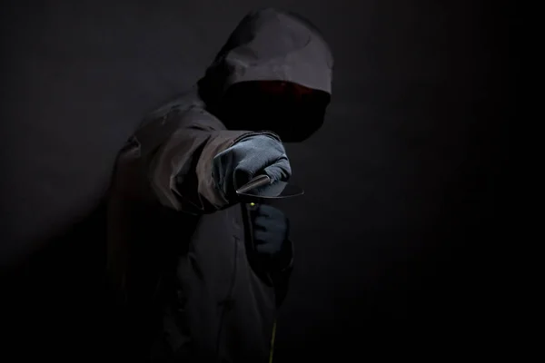 Killer in black holds the knife in aggressive style. Selective focus — Stock Photo, Image