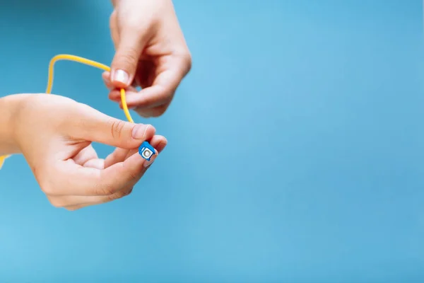 Kadınların elleri SC ve FC bağlayıcı fiber optik yama kablosunu mavi arkaplan üzerinde tutar