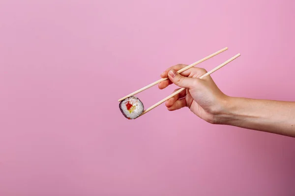 Maki de rolo de sushi saboroso com pauzinhos de madeira no fundo rosa perto. Lugar para legenda e texto — Fotografia de Stock