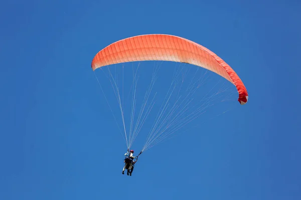 Blue Paraglider tandem instructeur met een toerist vliegen in de lucht met wolken op een zonnige dag — Stockfoto
